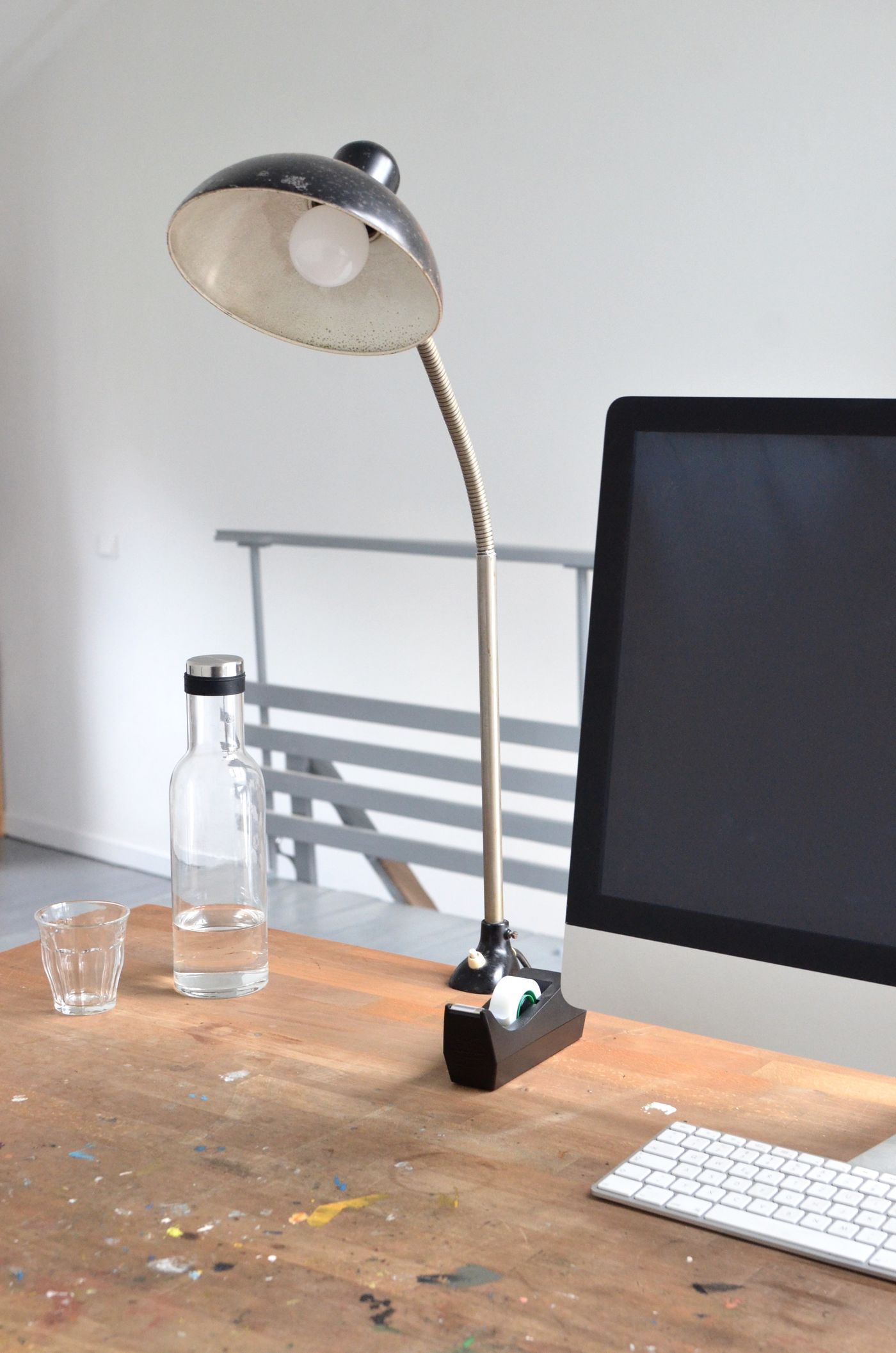 A computer and desk lamp on a wooden work surface