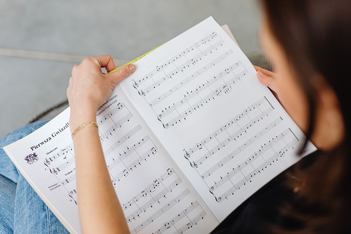 Hands holding open a book of printed music