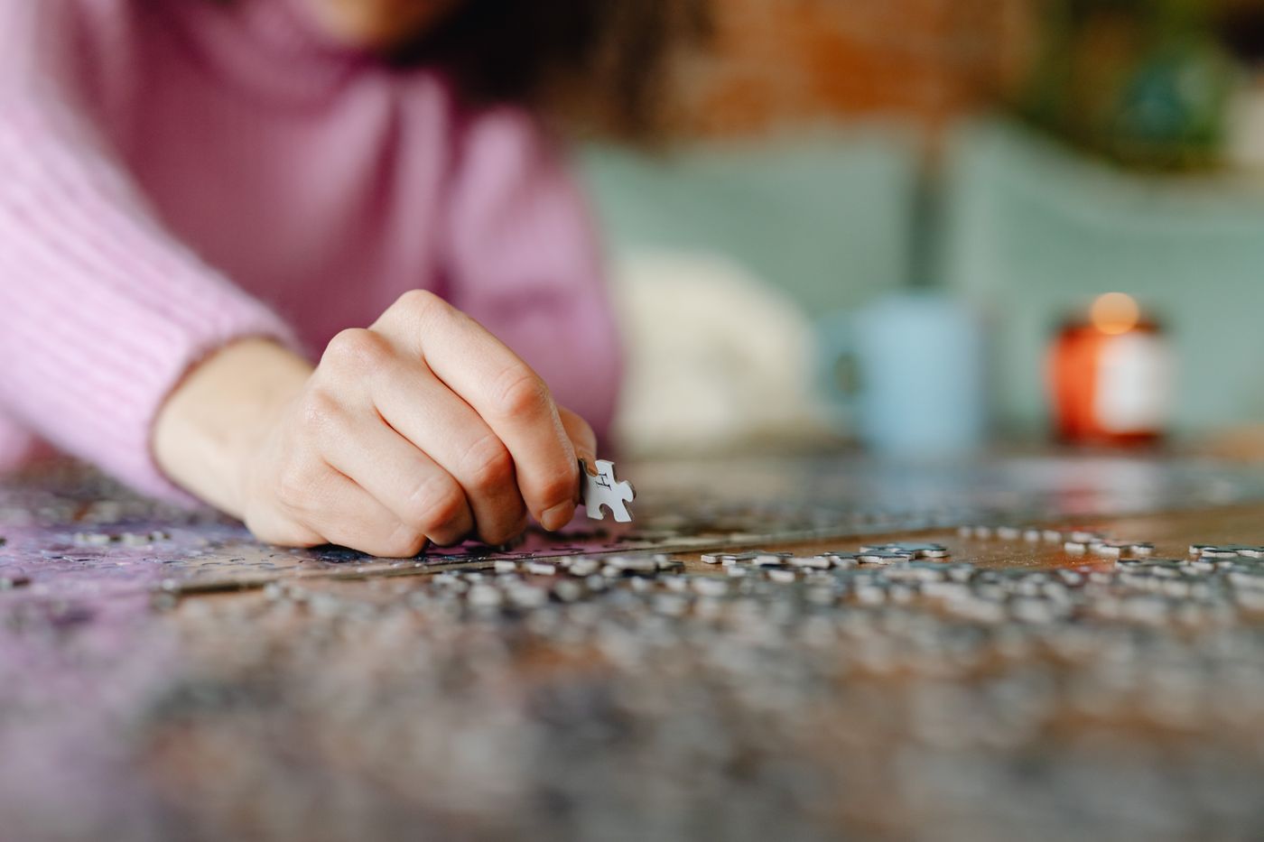A hand placing a piece into a partly assembled puzzle