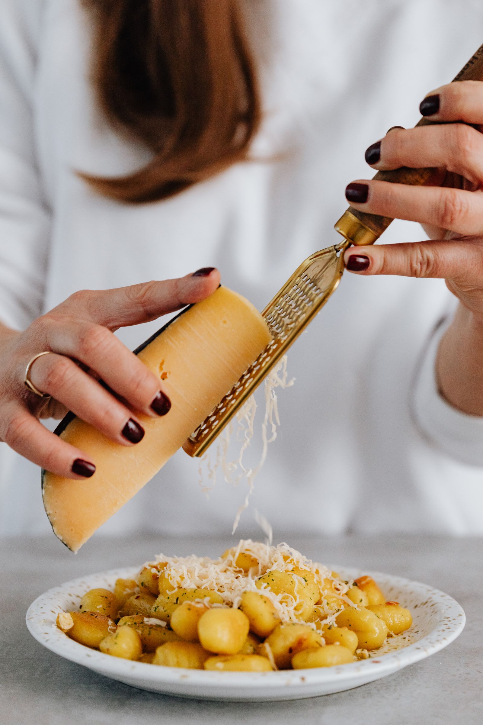 A person grating cheese over a prepared dish