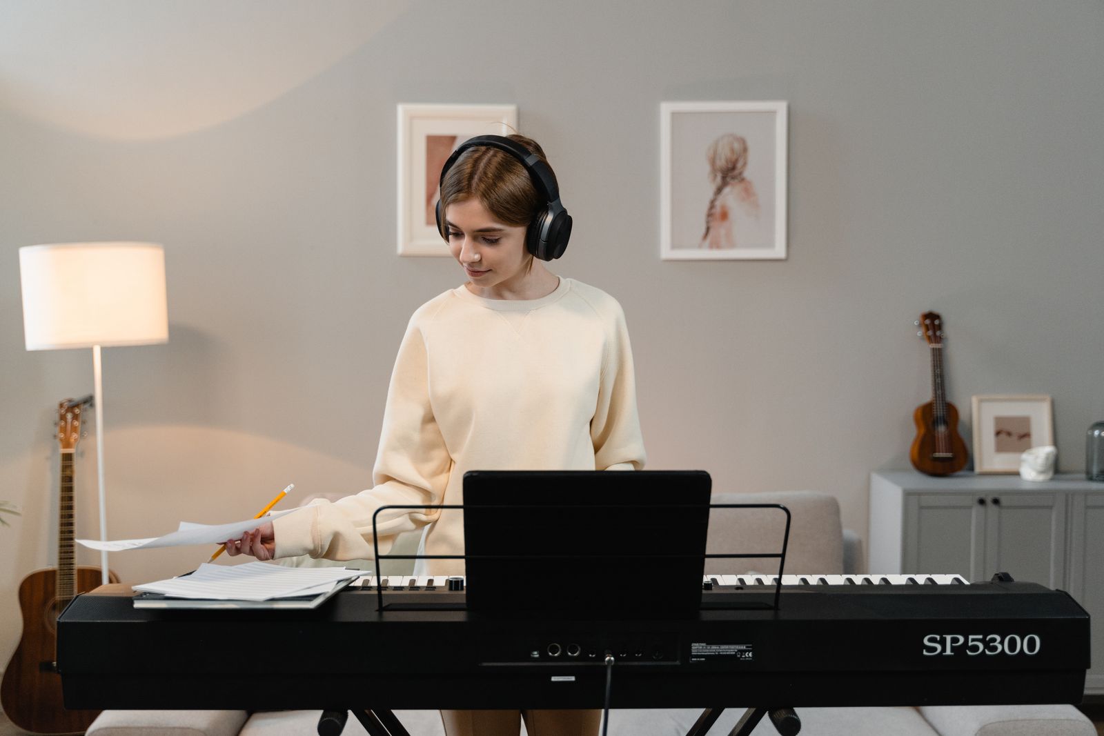 A person wearing headphones at a digital keyboard in a living room