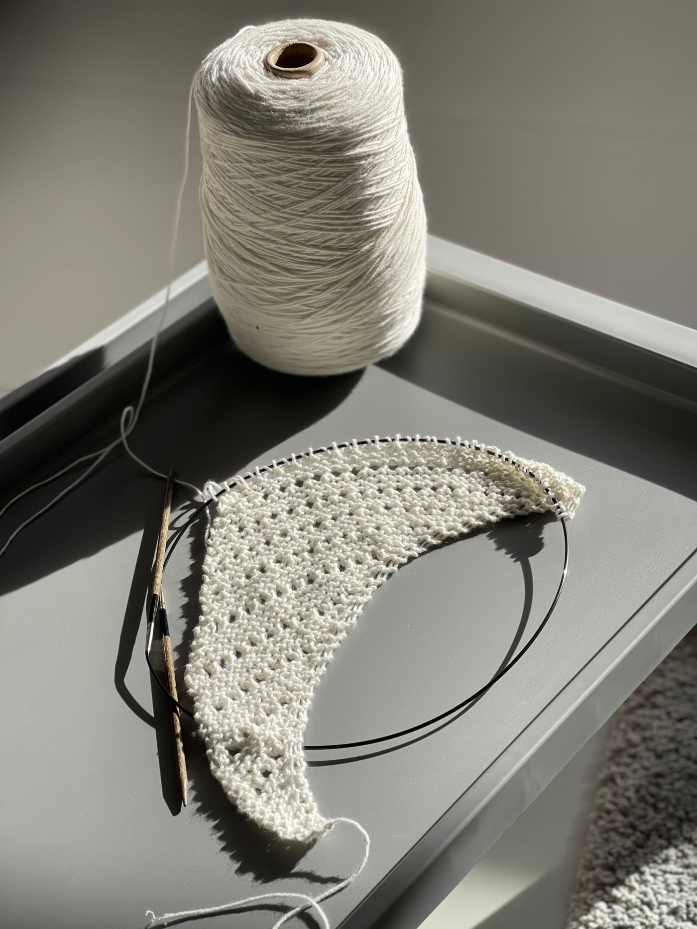 Crochet work and a yarn cone on a smooth surface