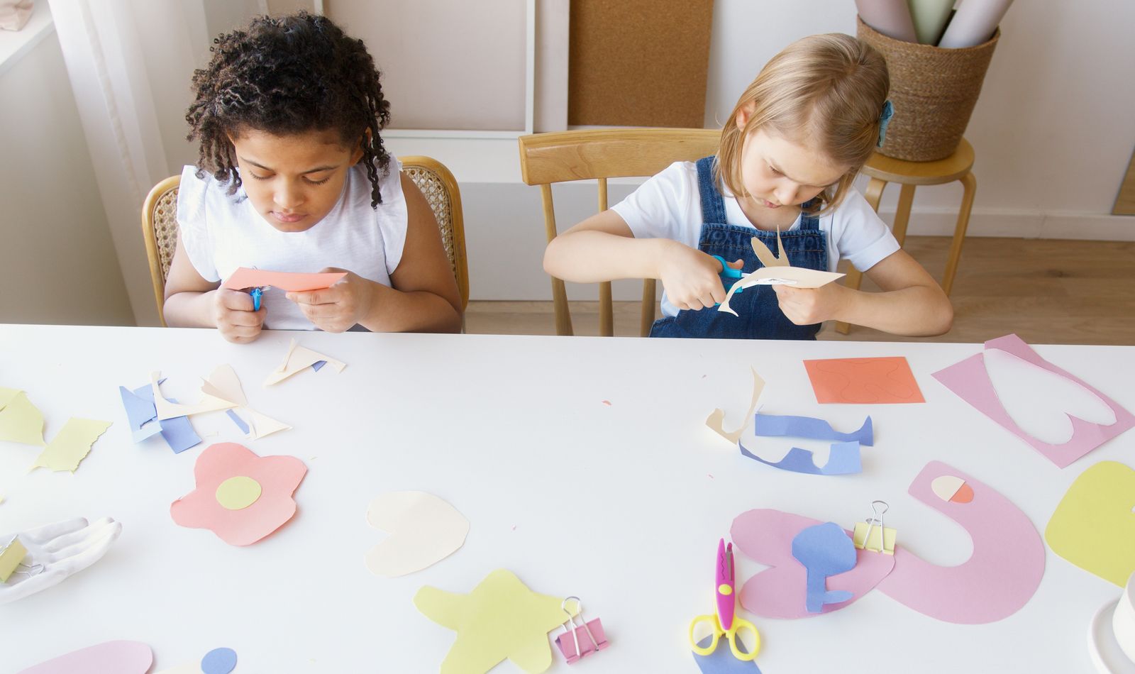 Two children working on colorful paper crafts