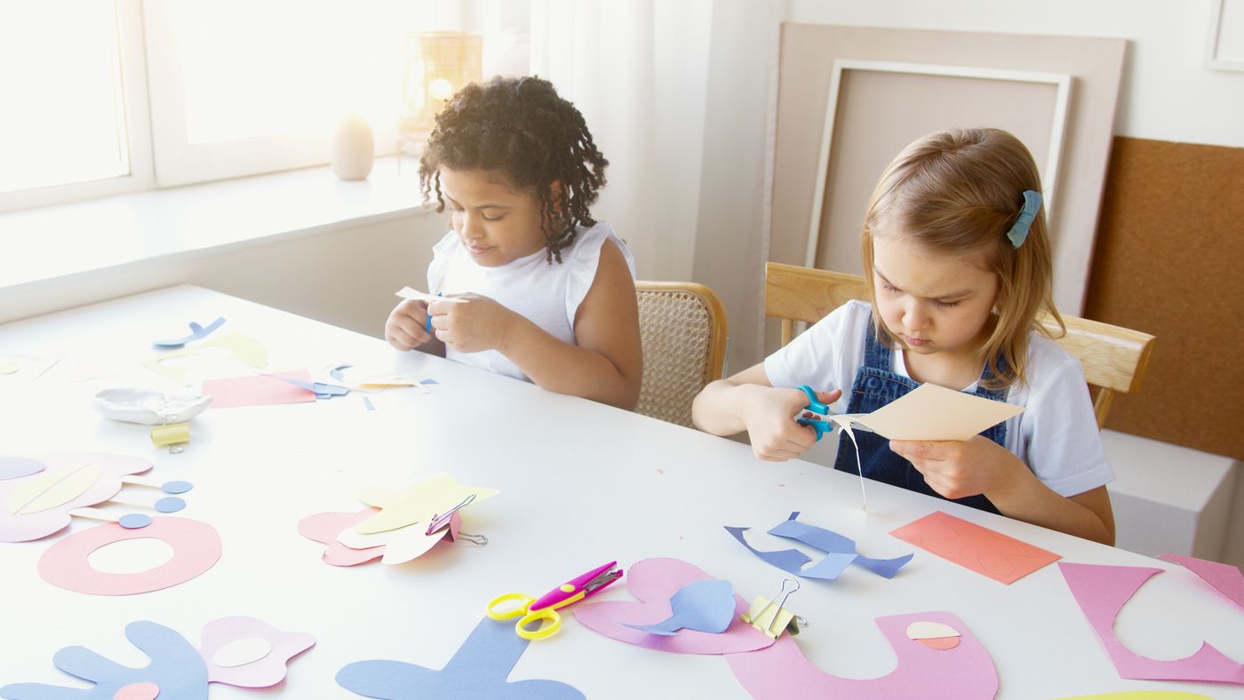 Children arranging colorful paper shapes at a table