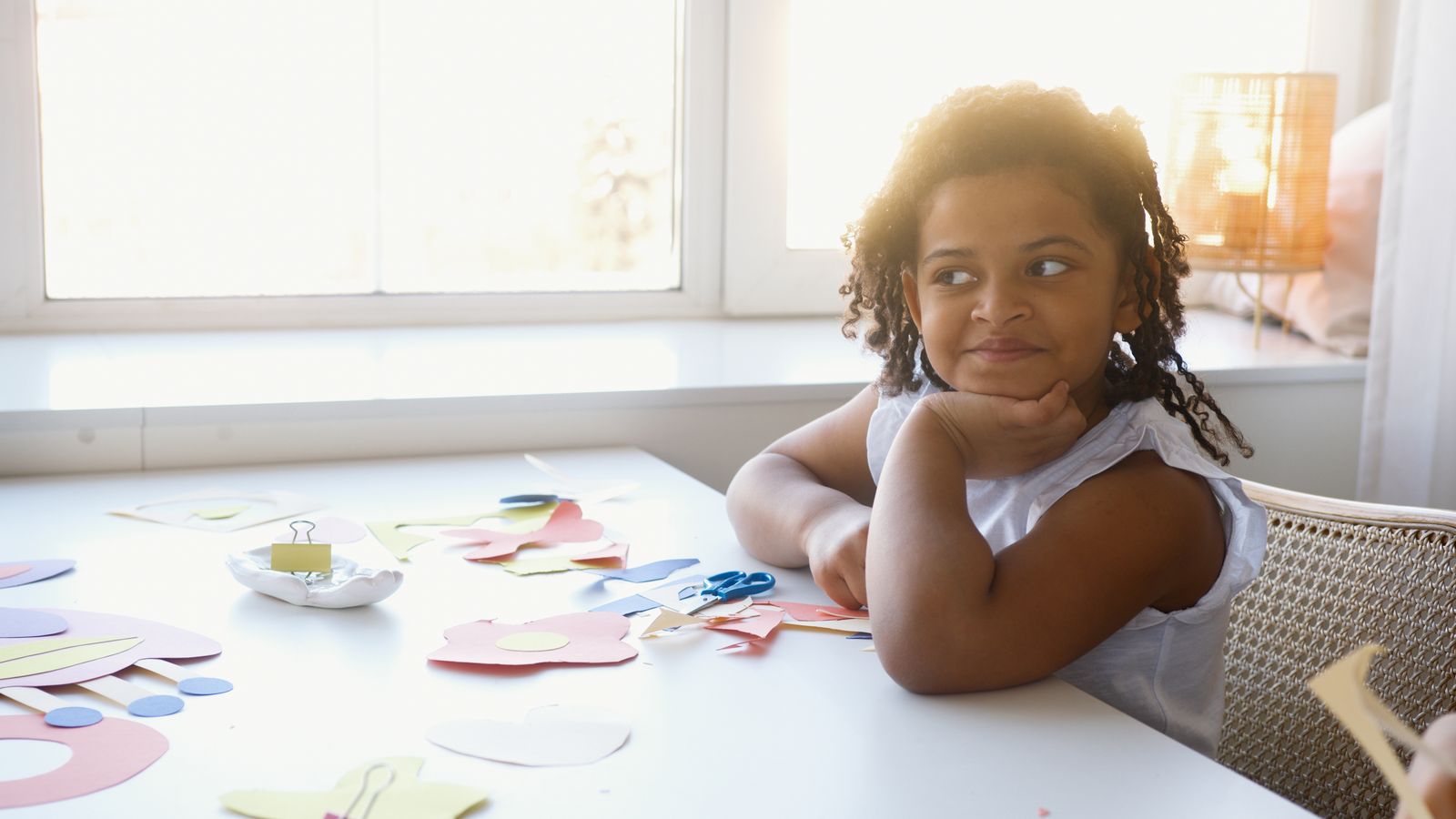 A child seated at a table with colorful craft supplies