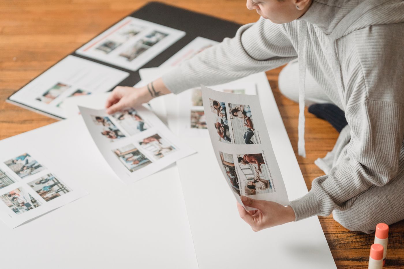 Printed photographs being arranged across white sheets; layout context