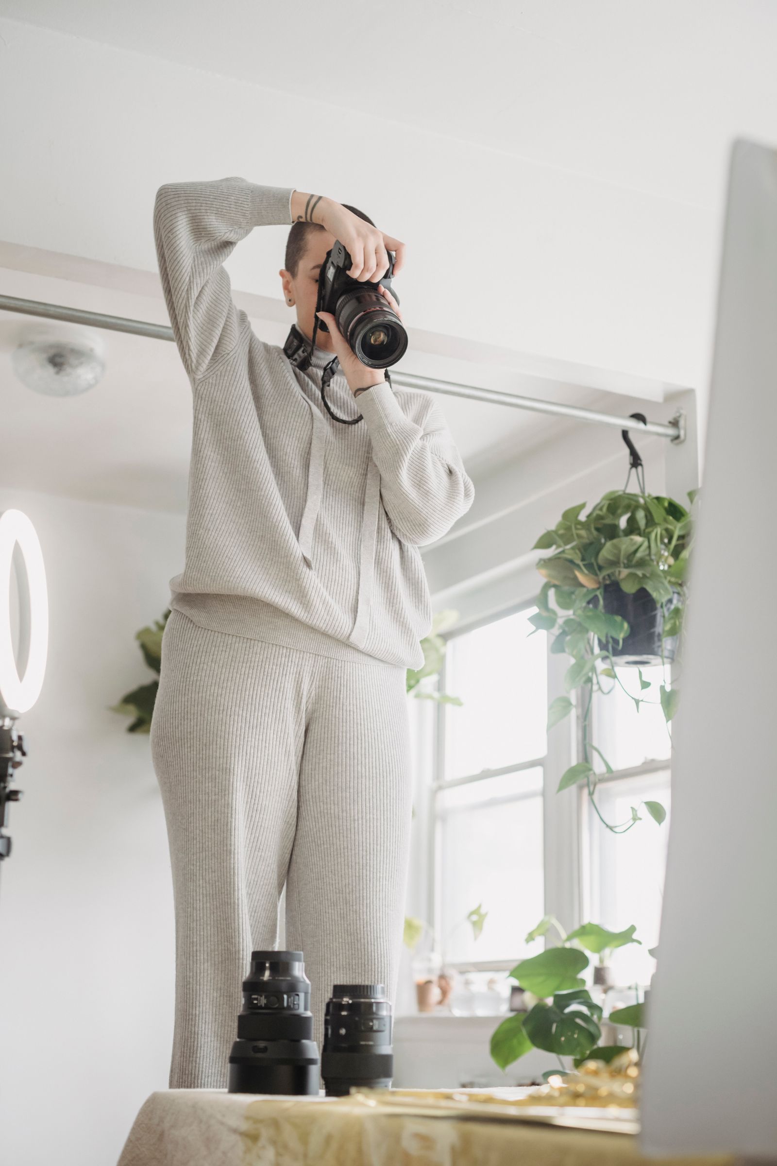 A photographer holding a camera beside a home-workspace table