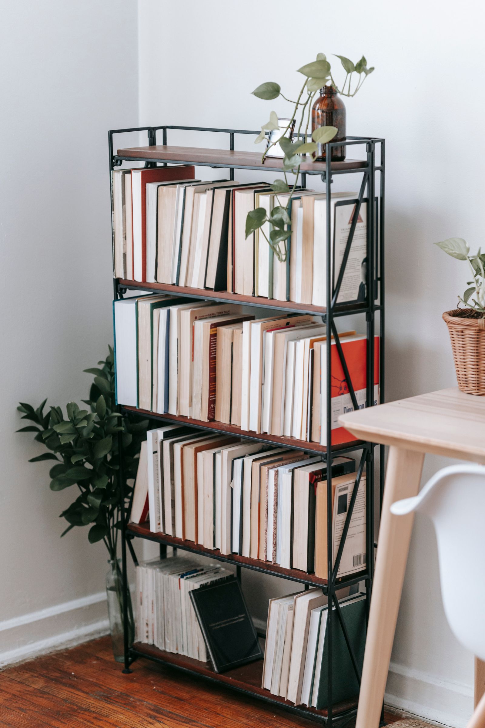 A bookcase beside a table and chair in a bright room