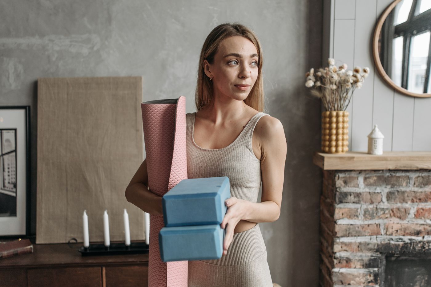 Person carrying a rolled mat and blocks in a home interior
