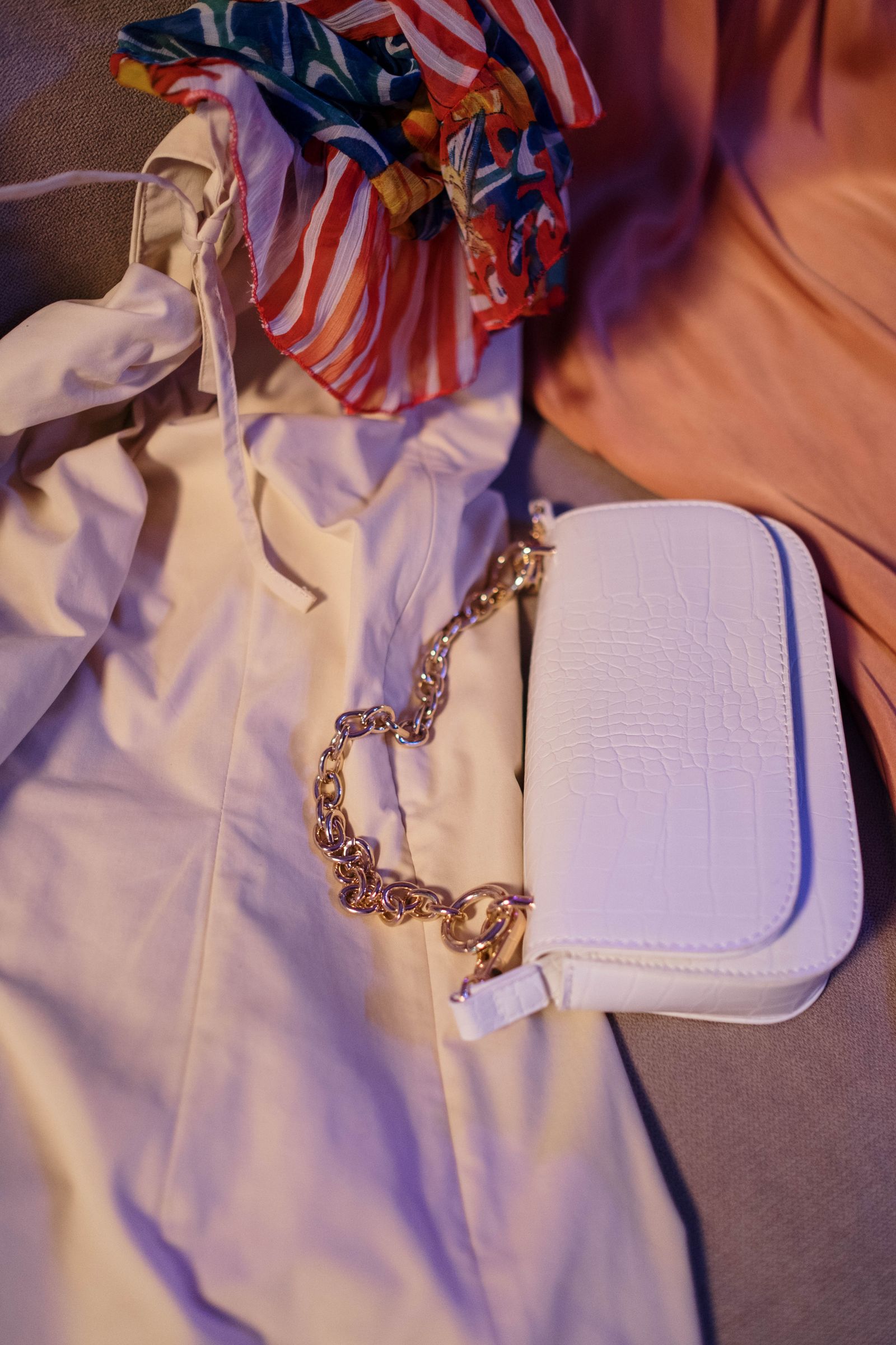 Colorful scarves beside a pale handbag