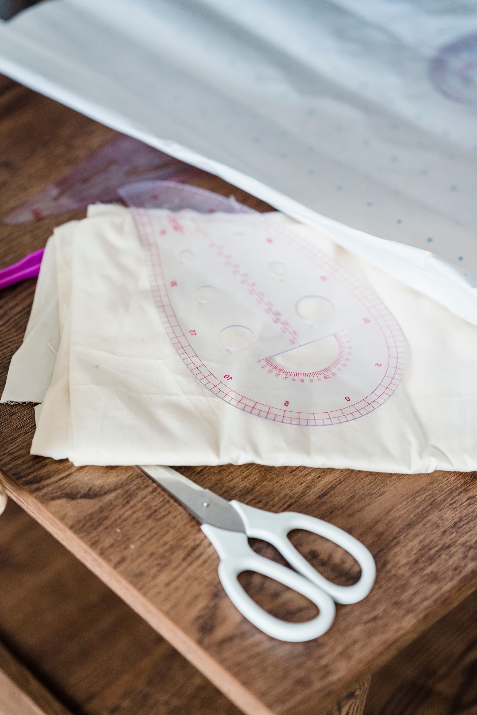 White scissors beside cut fabric on a wooden surface