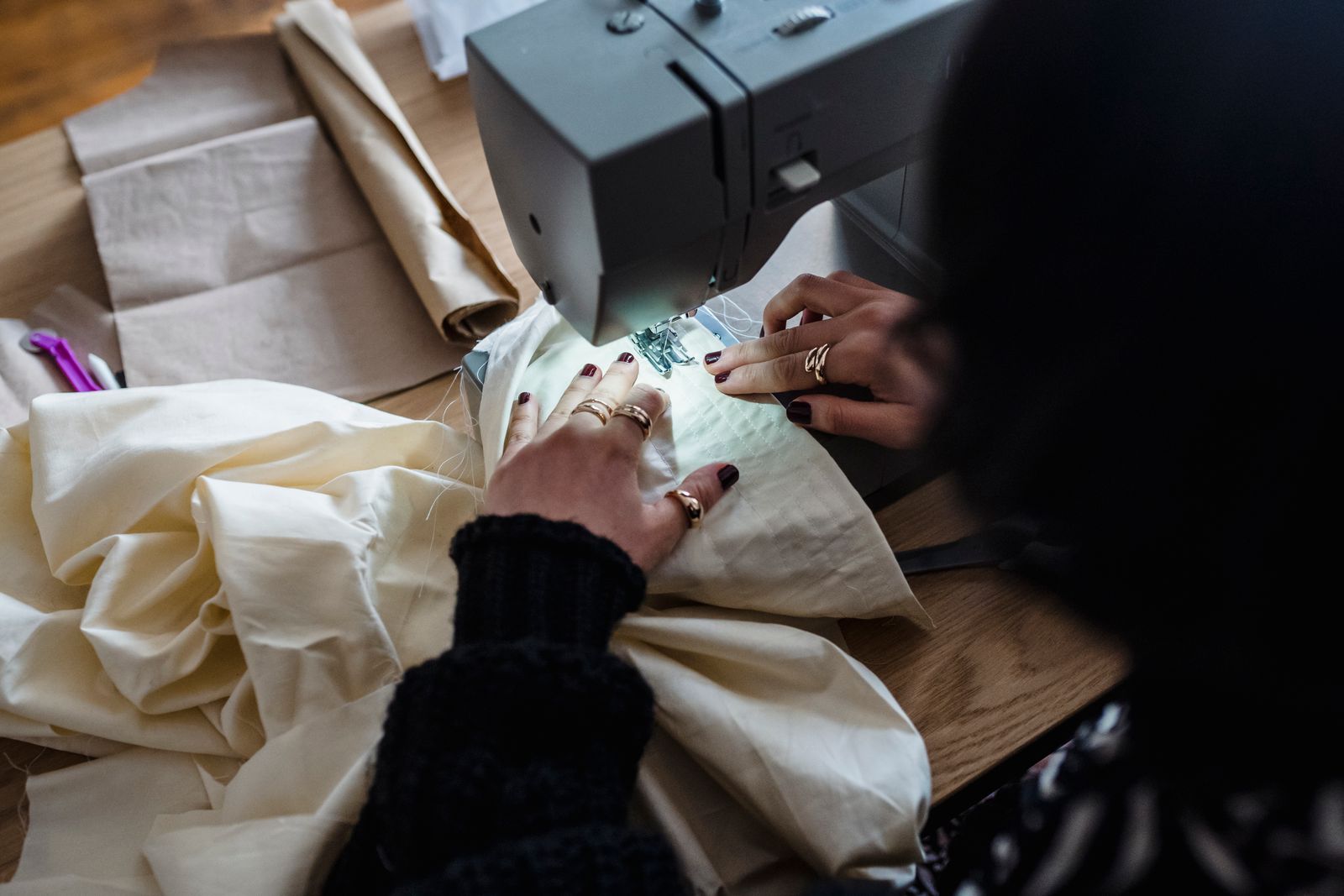 A person guiding fabric through a sewing machine