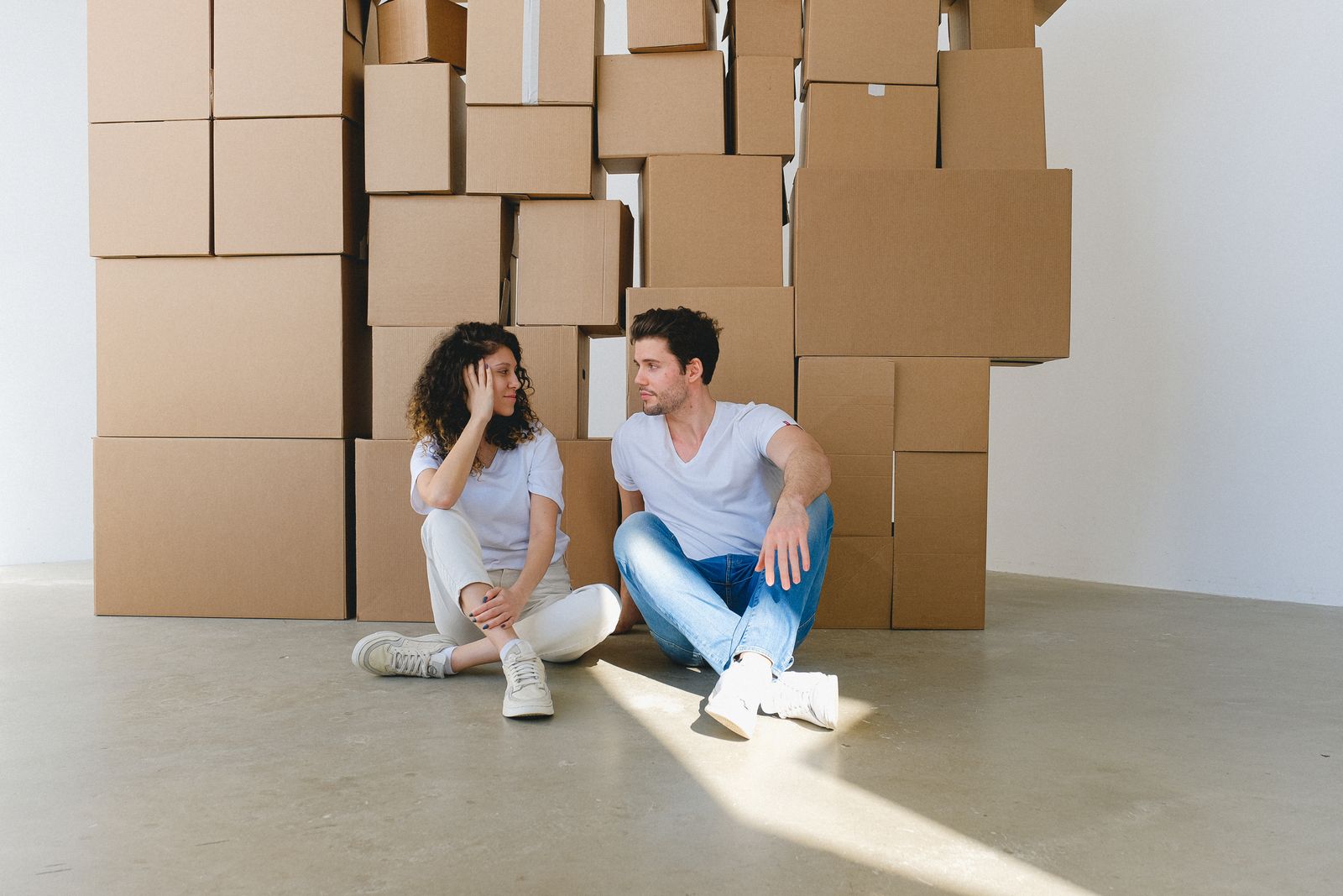 Two adults talking beside stacked boxes in an empty room