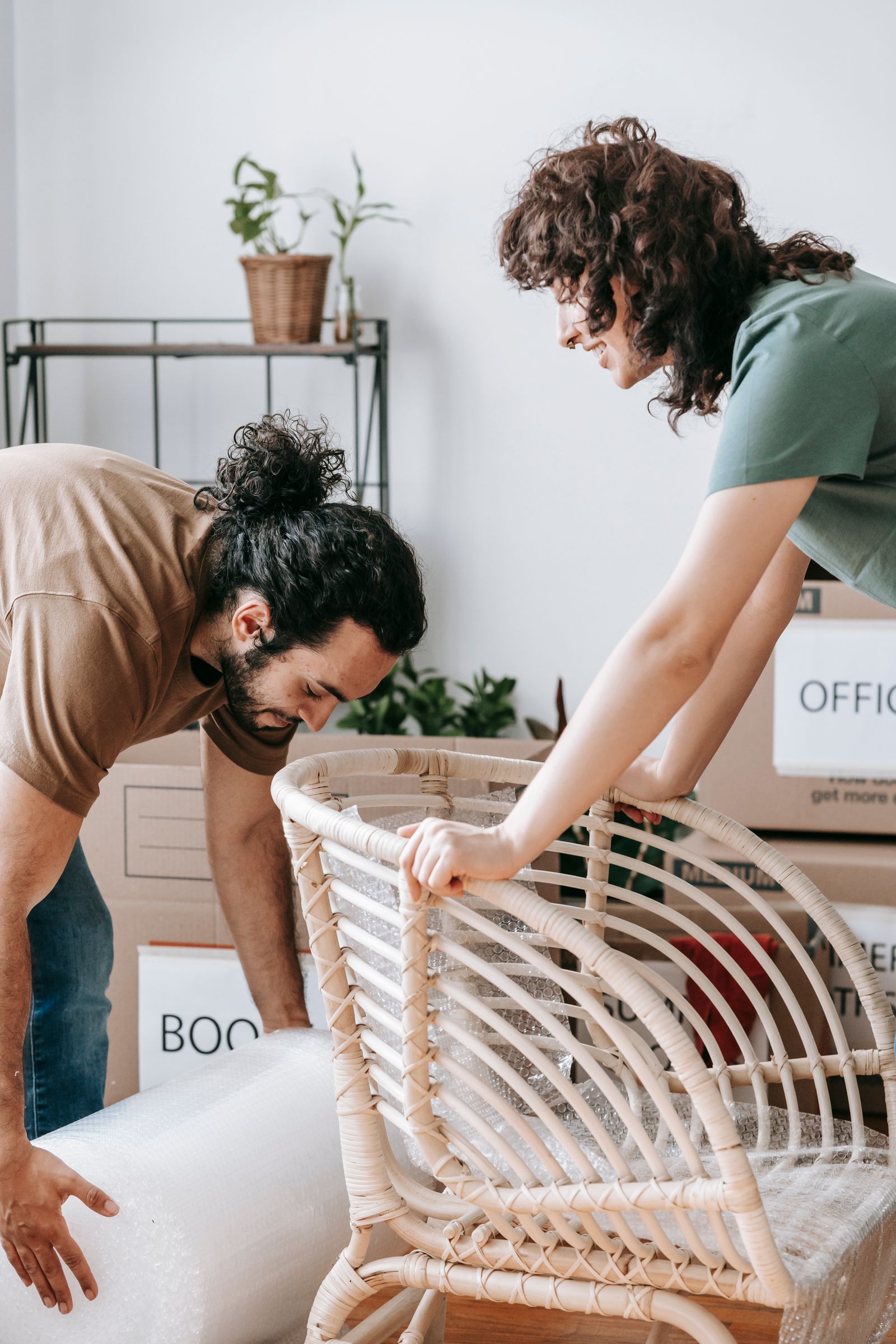 Two adults packing a chair beside moving boxes