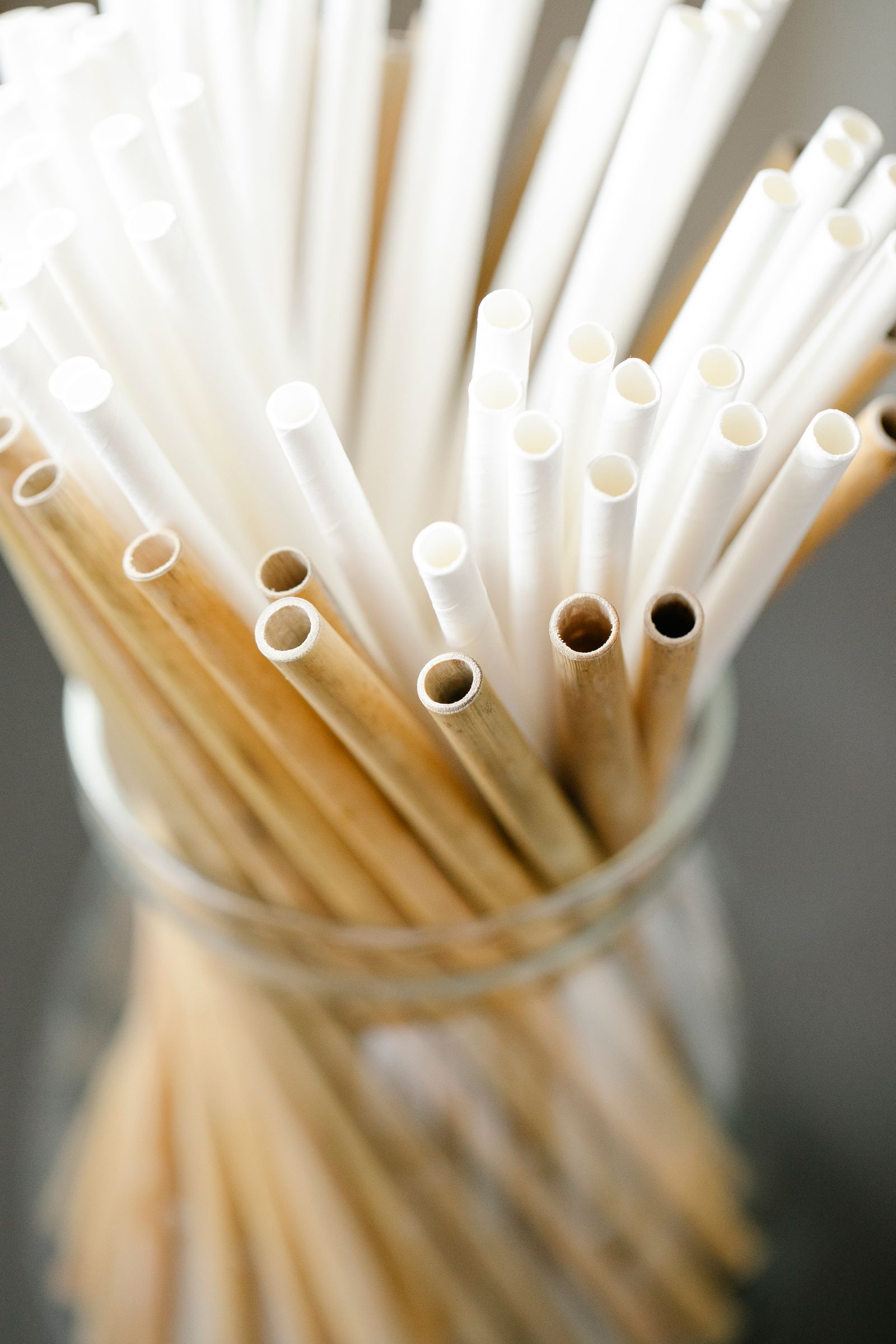 Light-colored reusable straws grouped in a glass jar