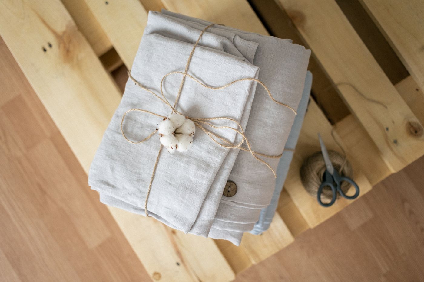 Folded light-colored linen fabric tied together on a wooden work surface