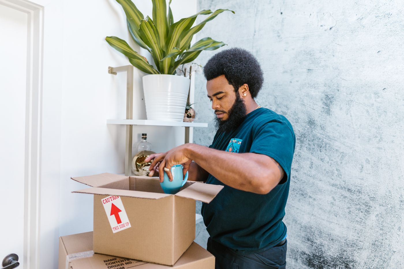 A person packing a ceramic object into a box
