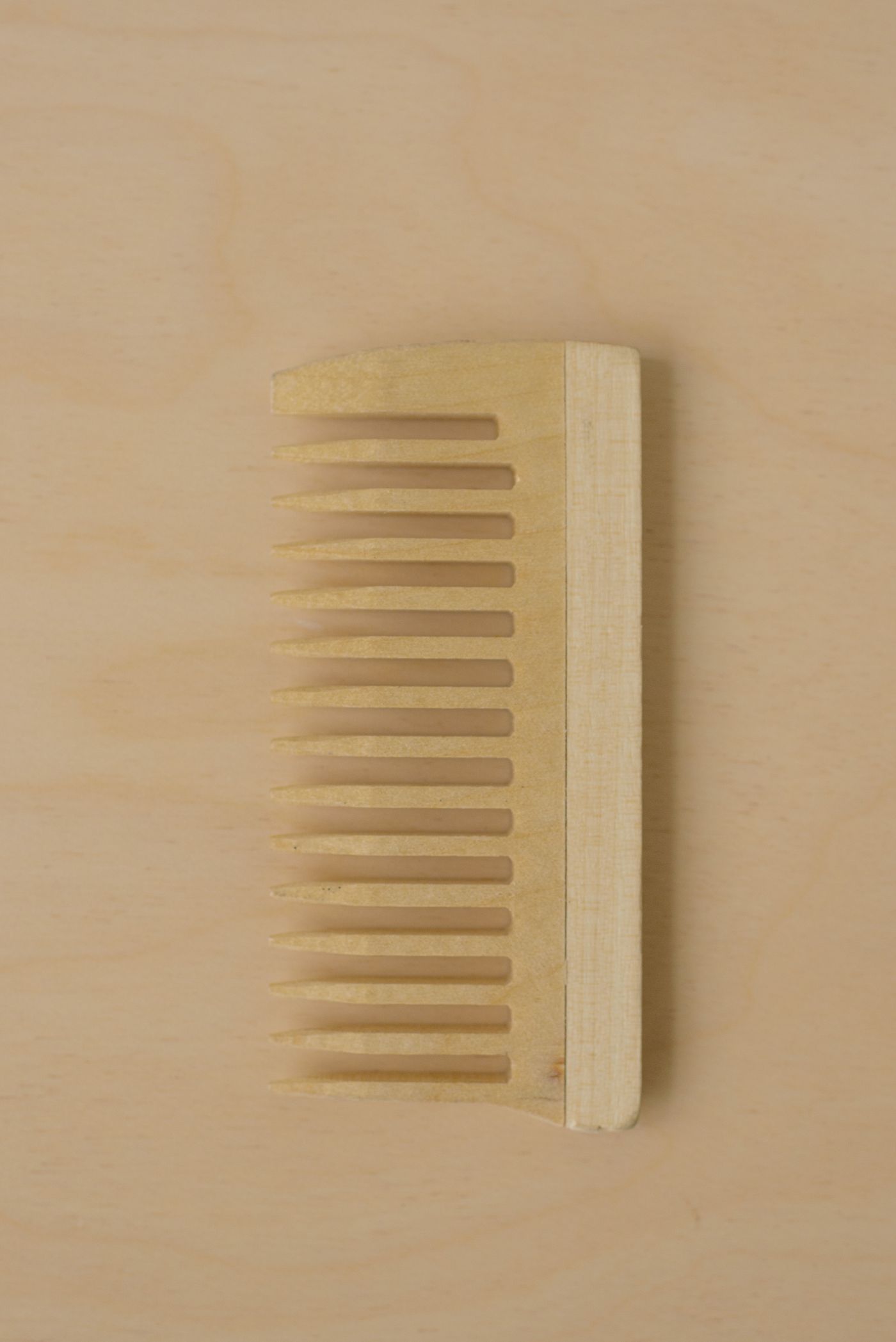 Wide-tooth wooden comb on a plain background