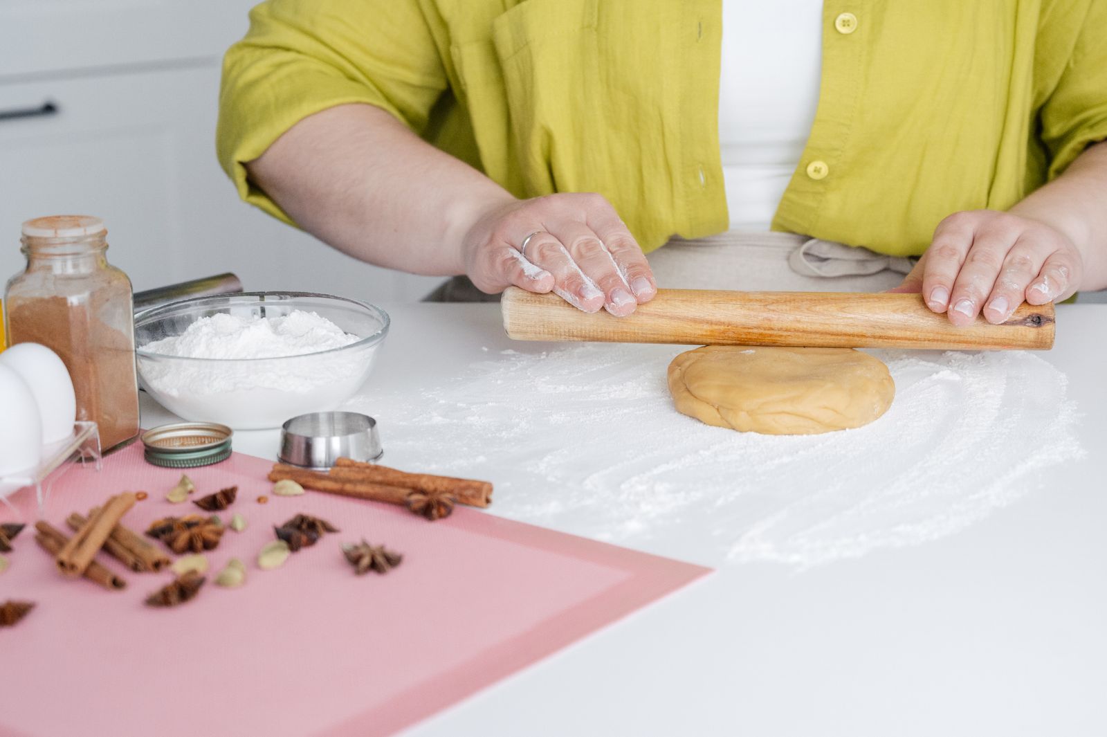 A person rolling dough beside baking equipment
