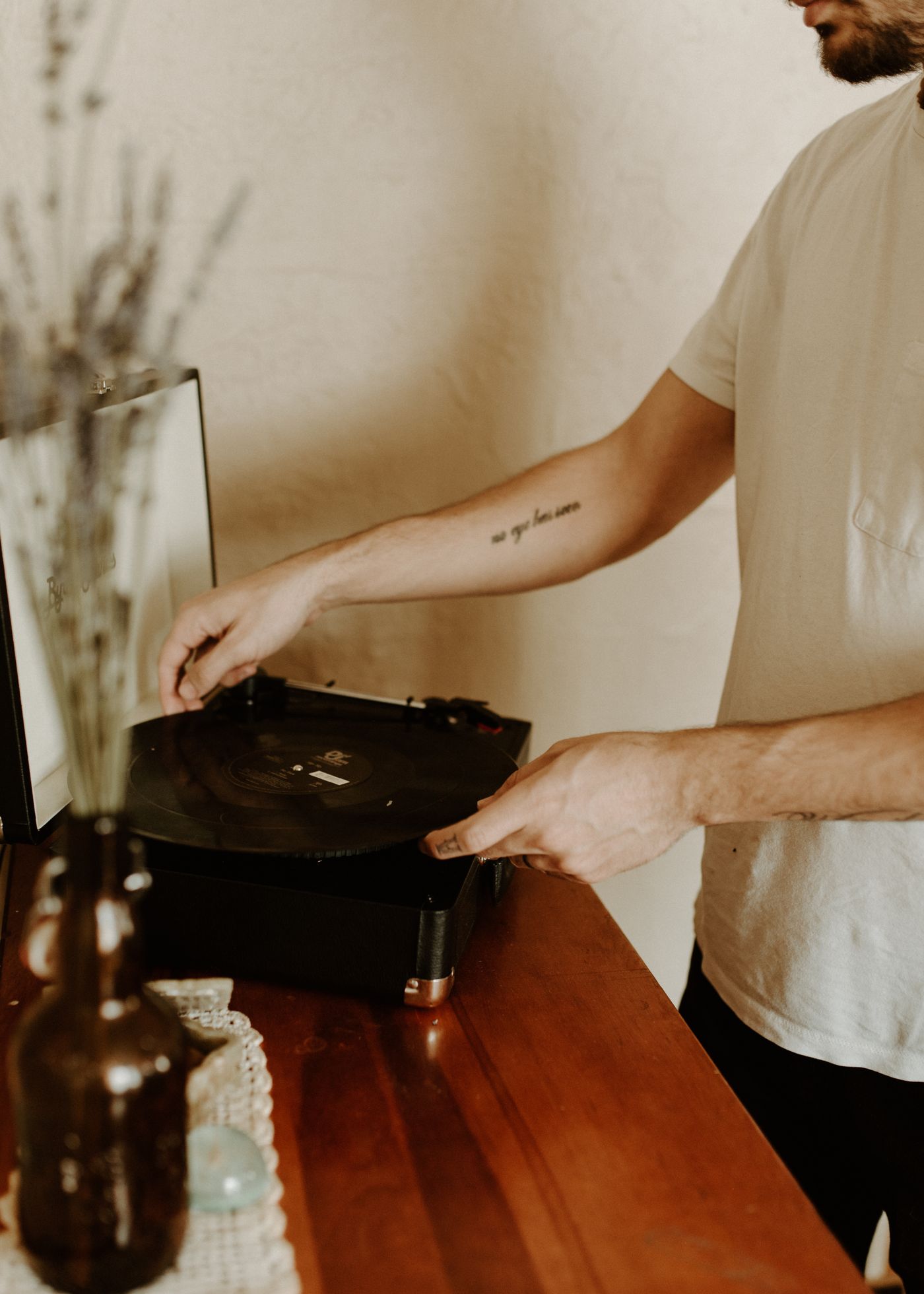 Hand operating a record player on a cabinet