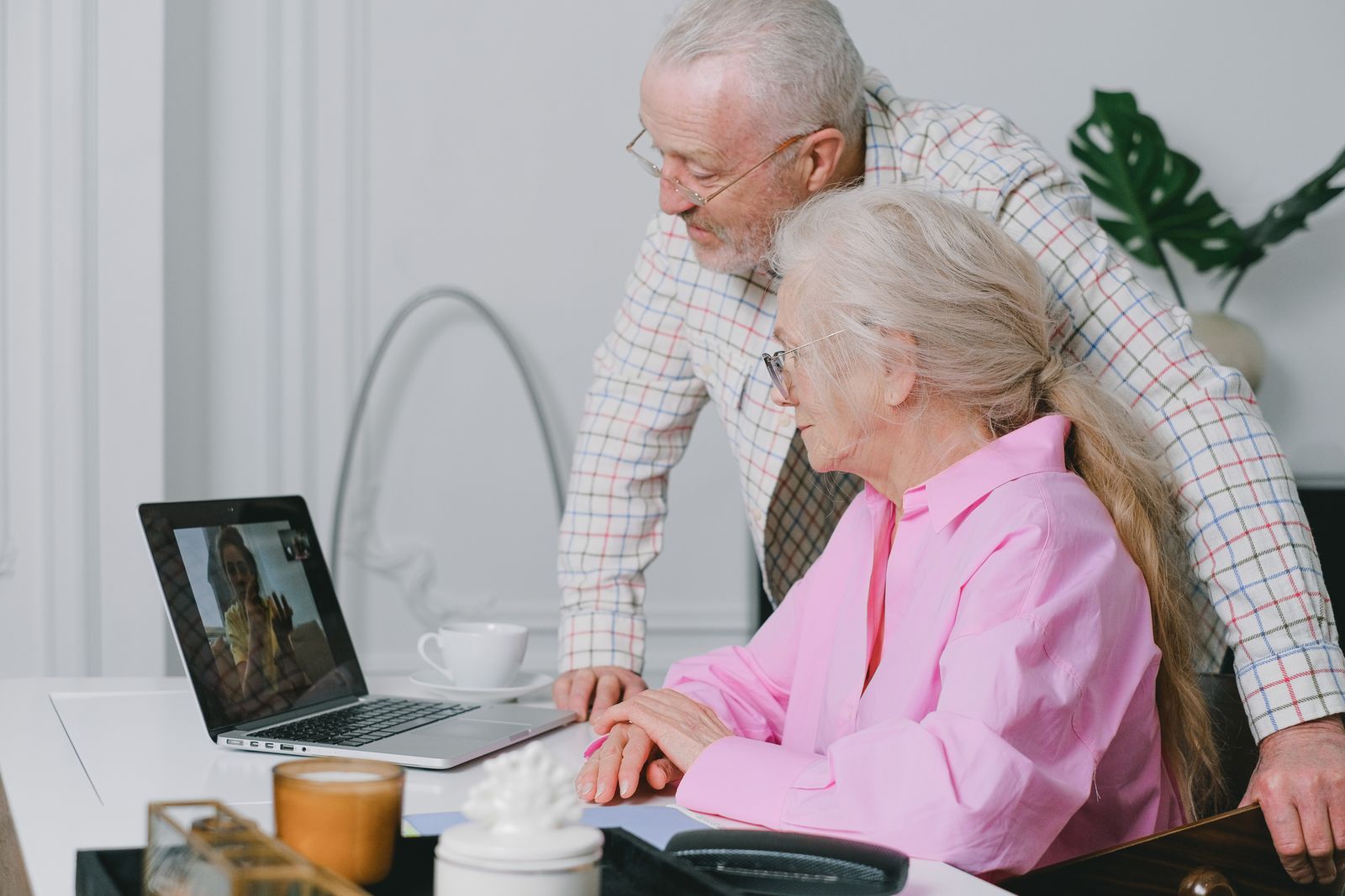 Two older people talking through a laptop at a table