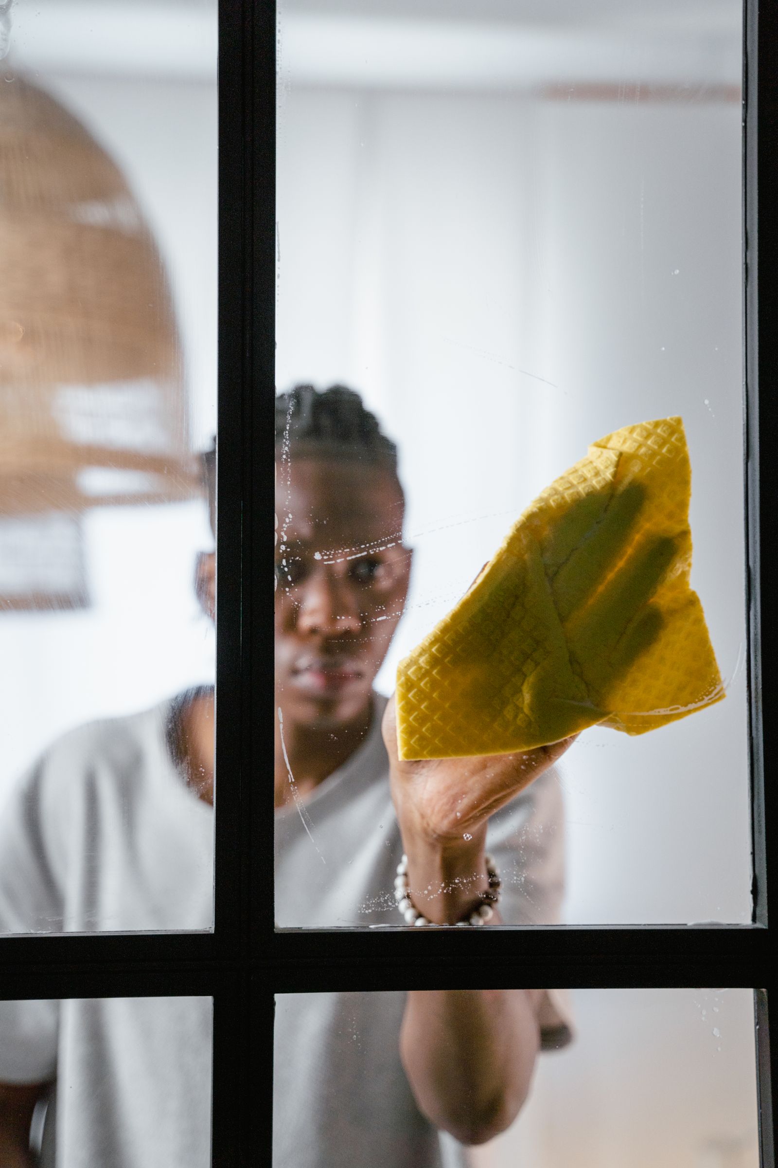 A person wiping window glass with a cloth
