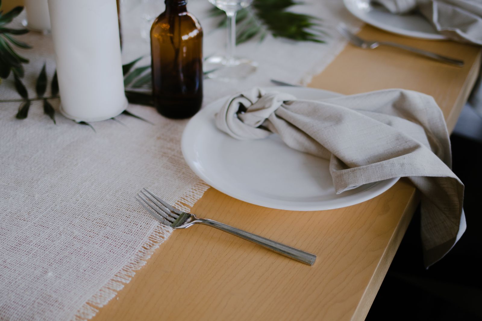 A pale fringed table textile beneath a plate and napkin