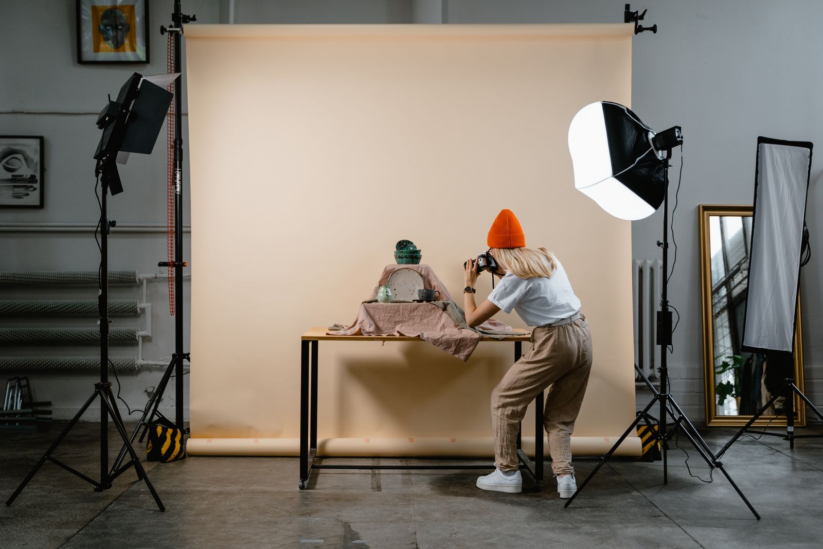 A photographer arranging ceramic pieces under studio lights