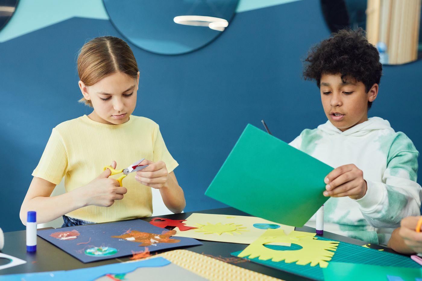 Children cutting colored paper for a shared craft session