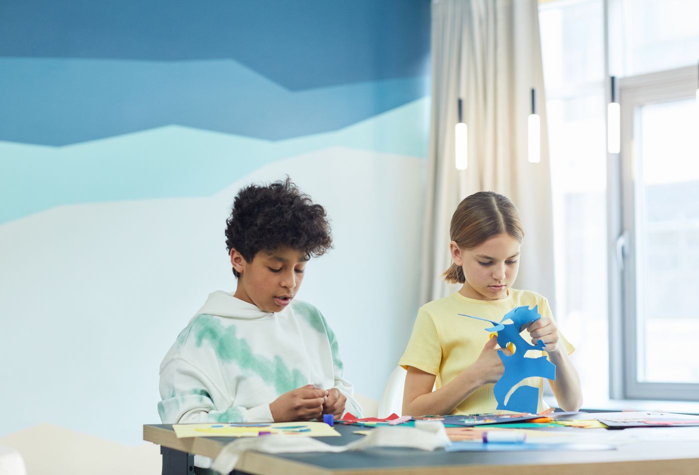 Two children arranging cut paper shapes