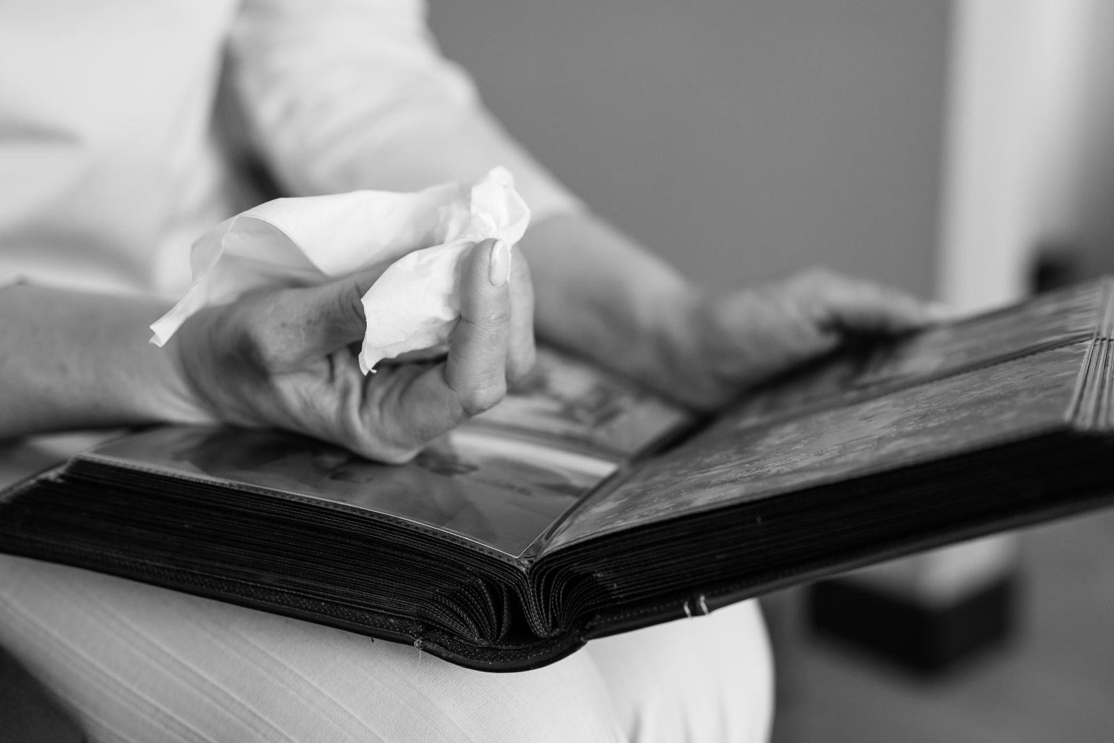 Hands resting on an open photo album in black and white