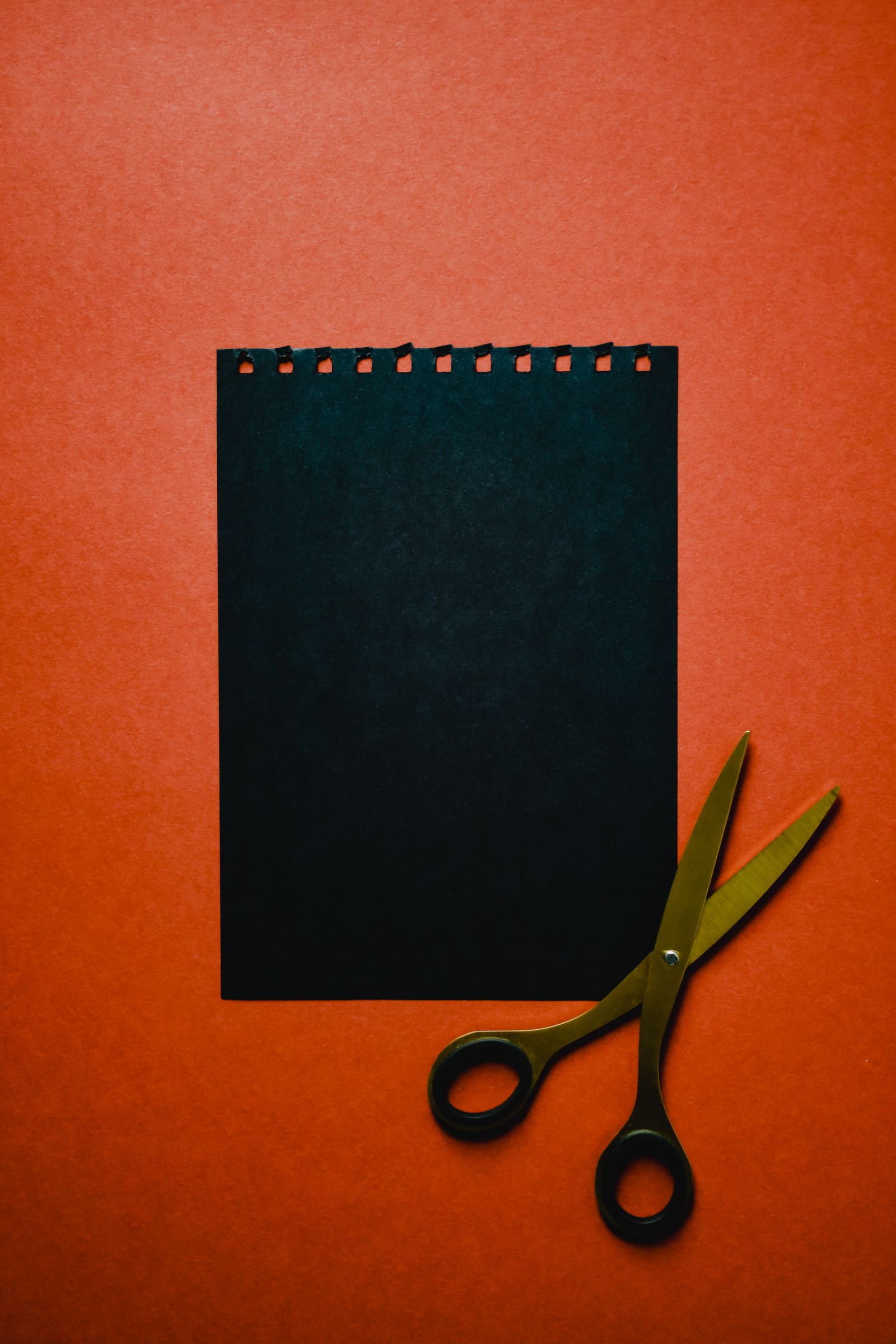 Black paper and scissors on a red surface