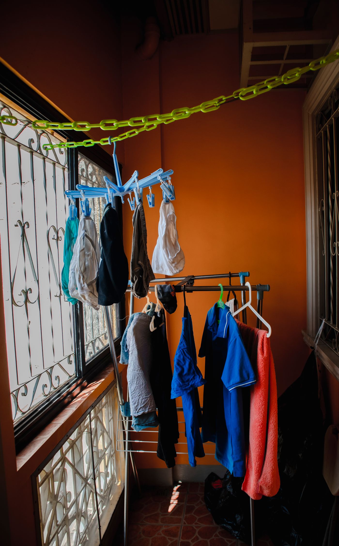 Several hanging garments and drying supports near a window