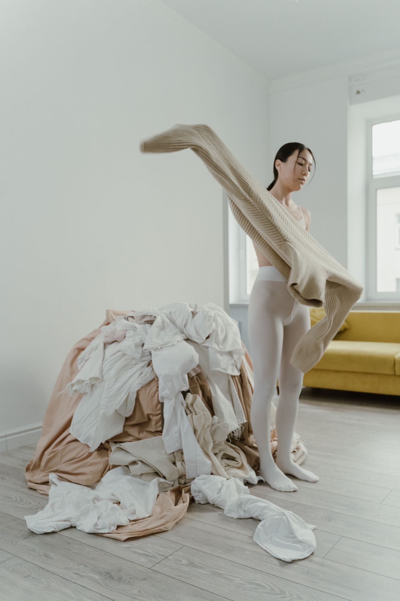 Person handling a textile beside a laundry pile; care-workflow context