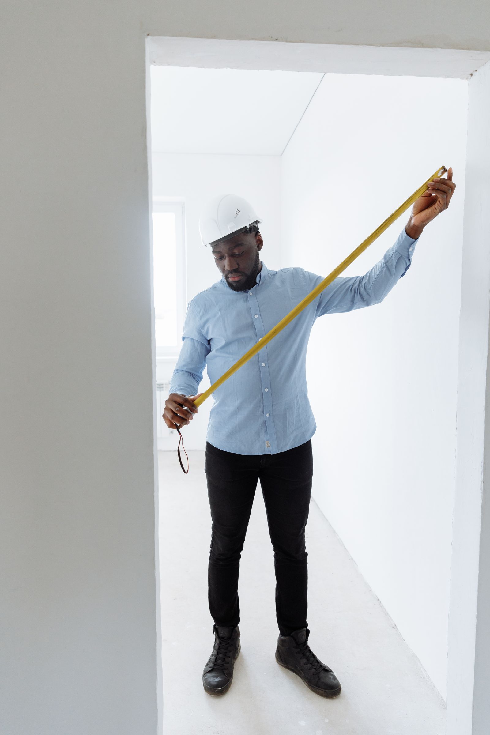 A person extending a tape measure inside a room