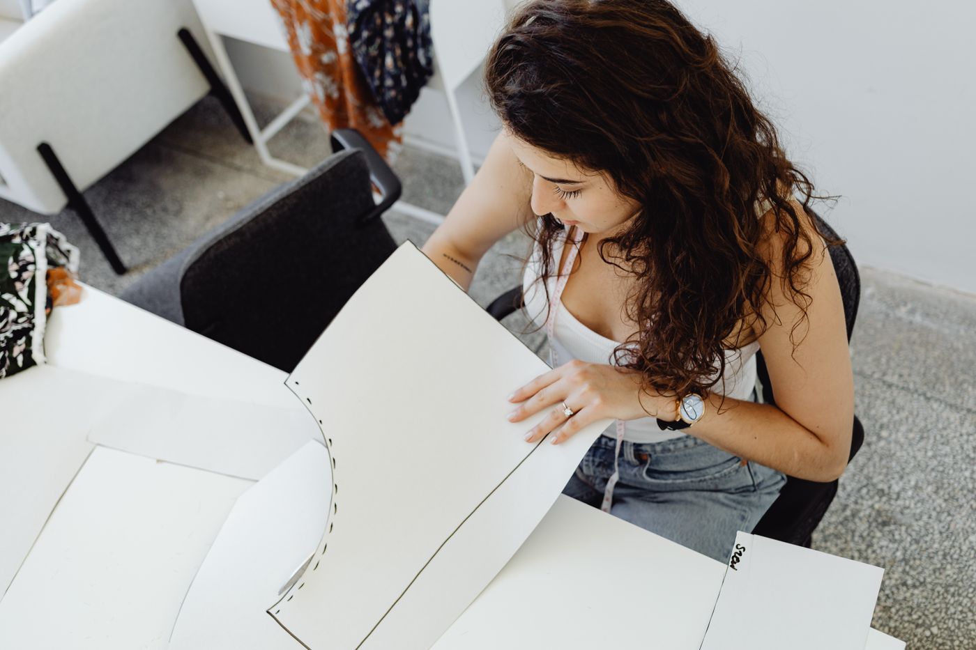 A person drawing a paper sewing pattern at a table