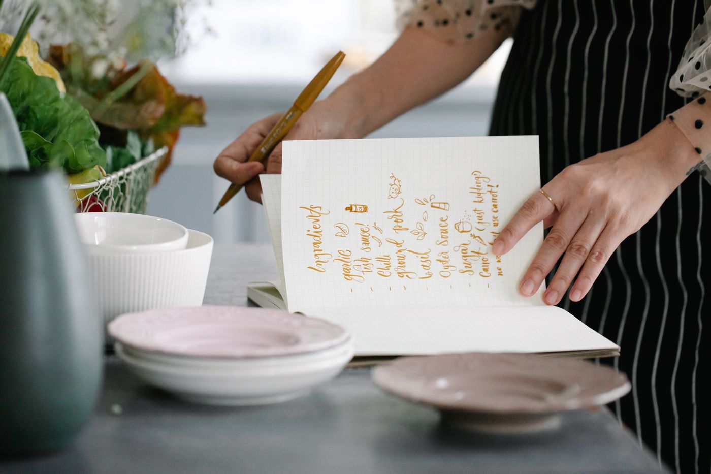 Hands recording kitchen notes in a notebook