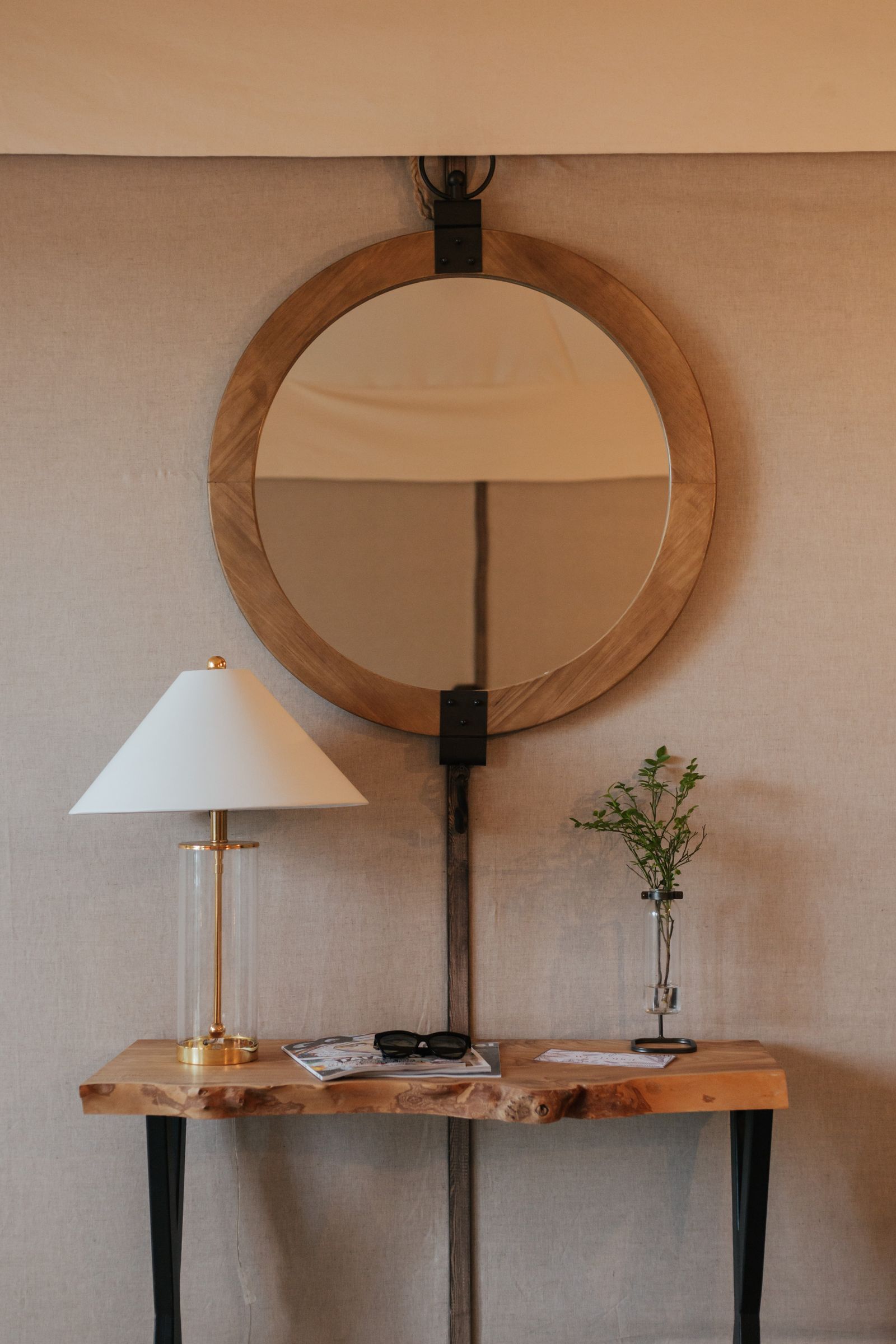A console table with a round mirror and a lamp