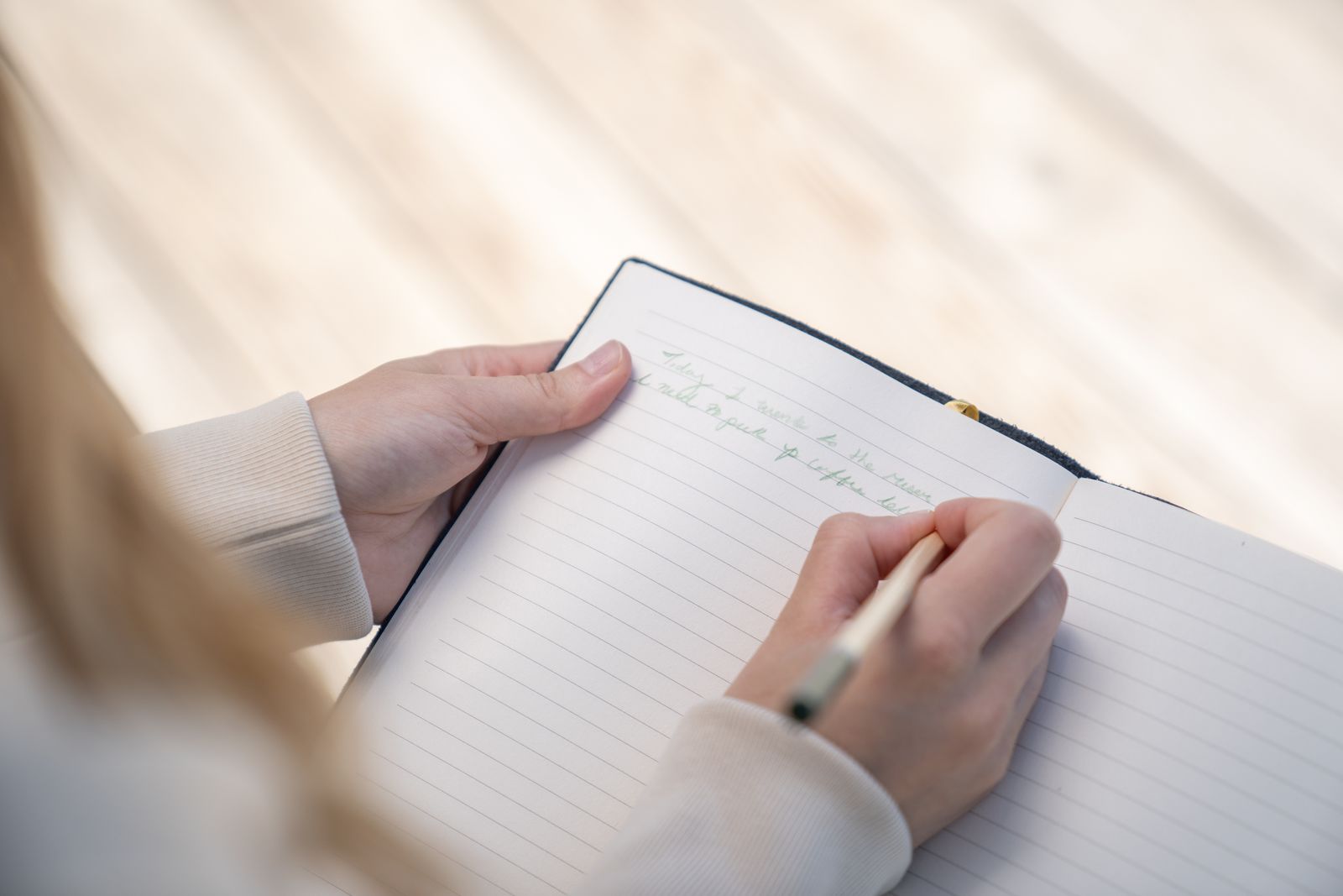 A person writing in a lined notebook beside a table