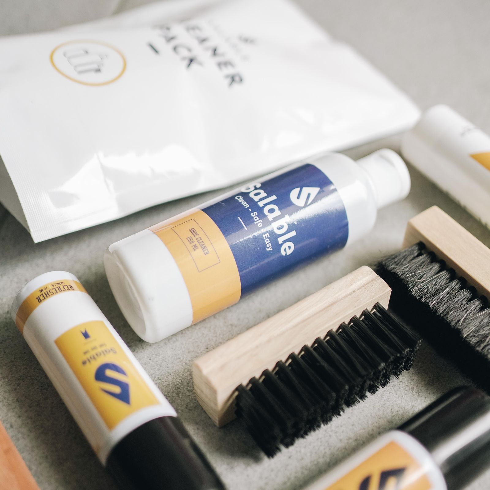 Shoe-care containers and brushes on a pale surface