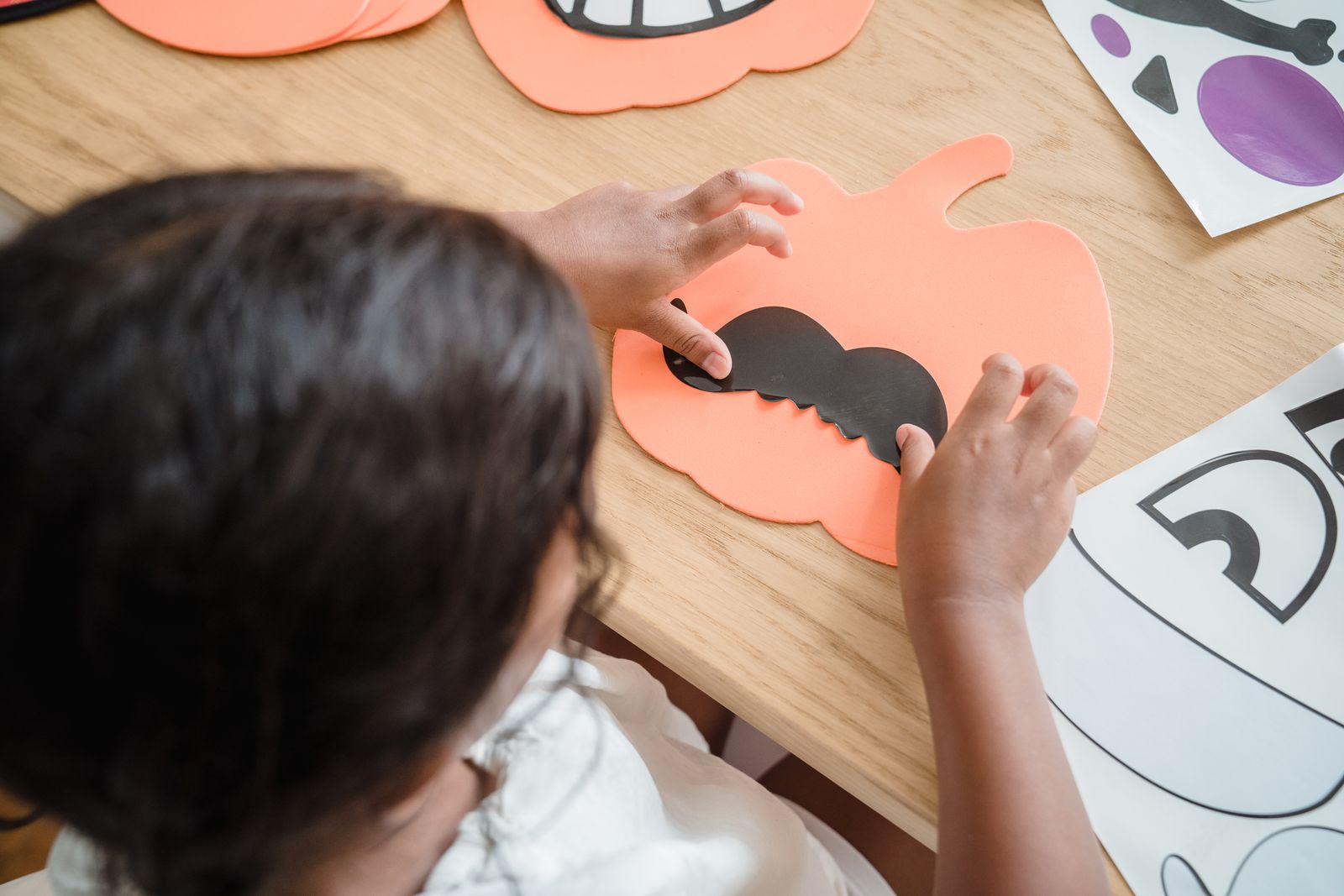 A child making paper pumpkin decorations at a table