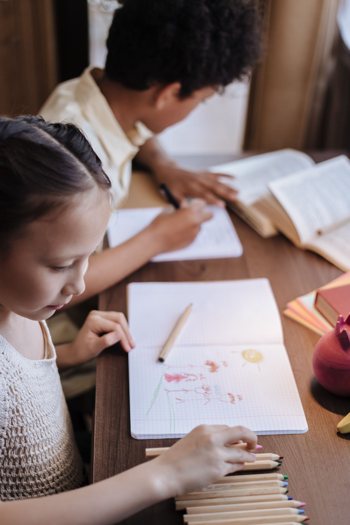 Adult beside a child drawing on a separate sheet