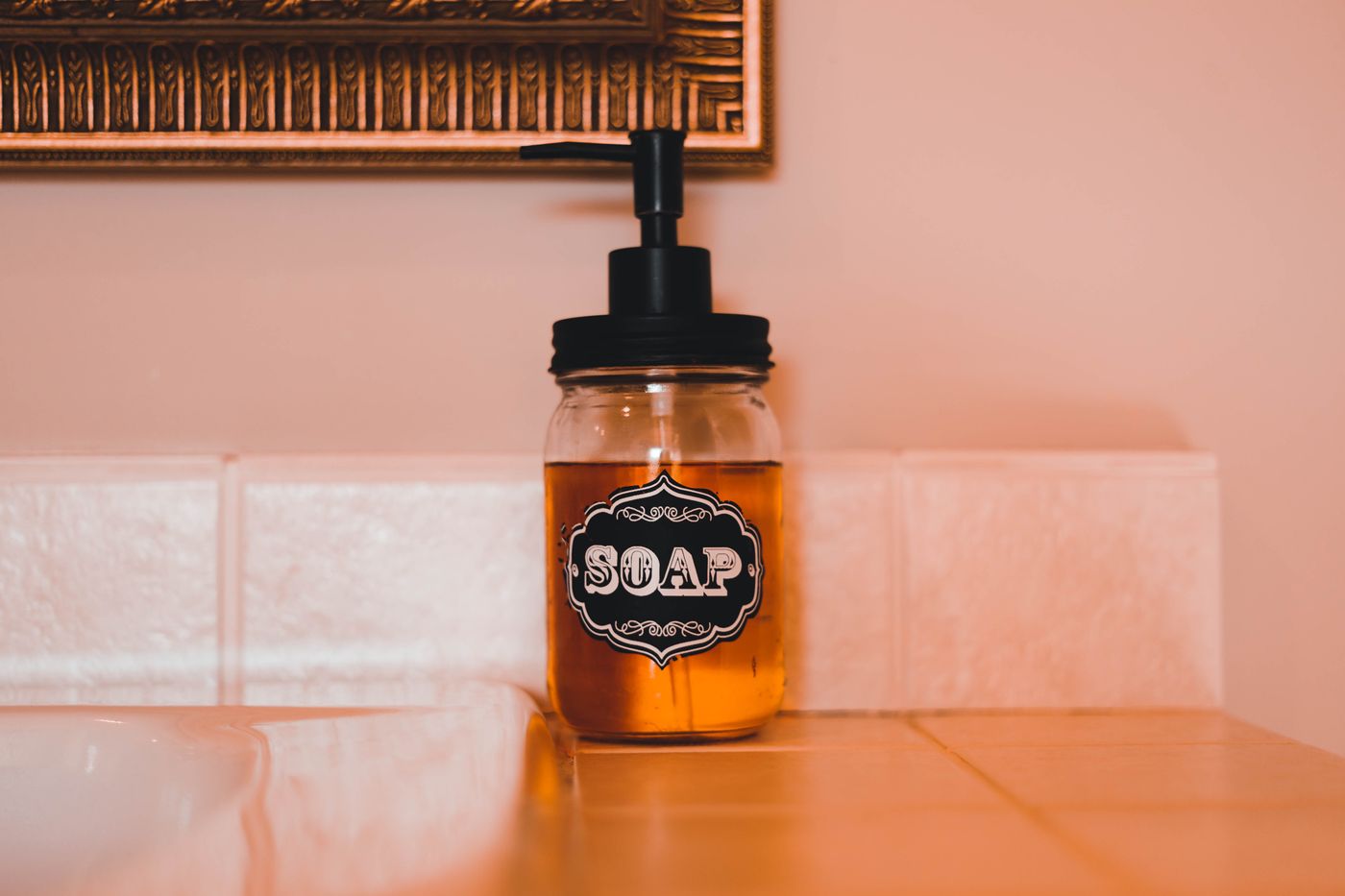 An amber pump bottle on a tiled bathroom ledge